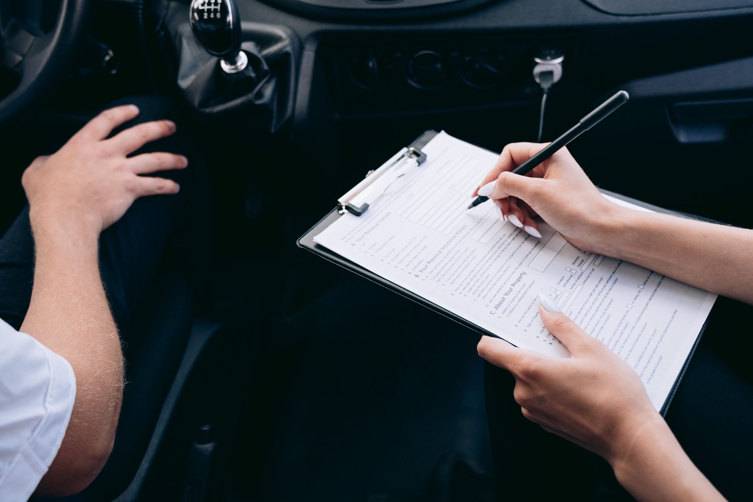 Person filling out a claim inspection form inside a car