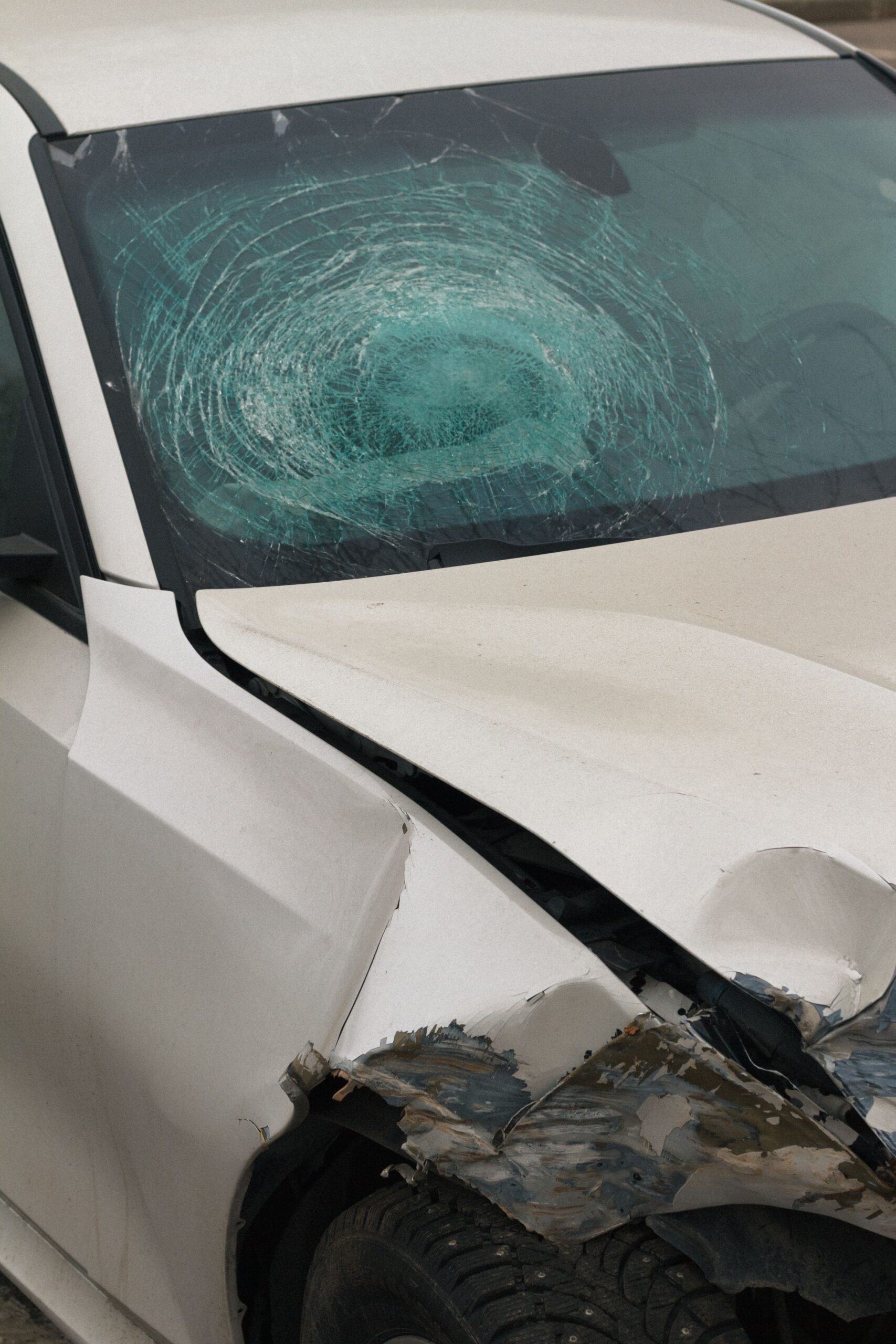 Car with shattered windshield and front-end damage after an accident