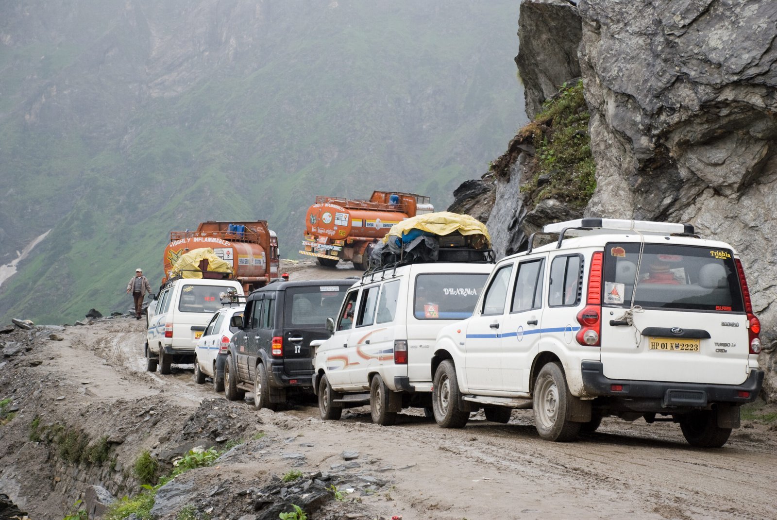 A queue of mixed vehicles including an SUV and an MPV stuck in traffic on a mountain road in India