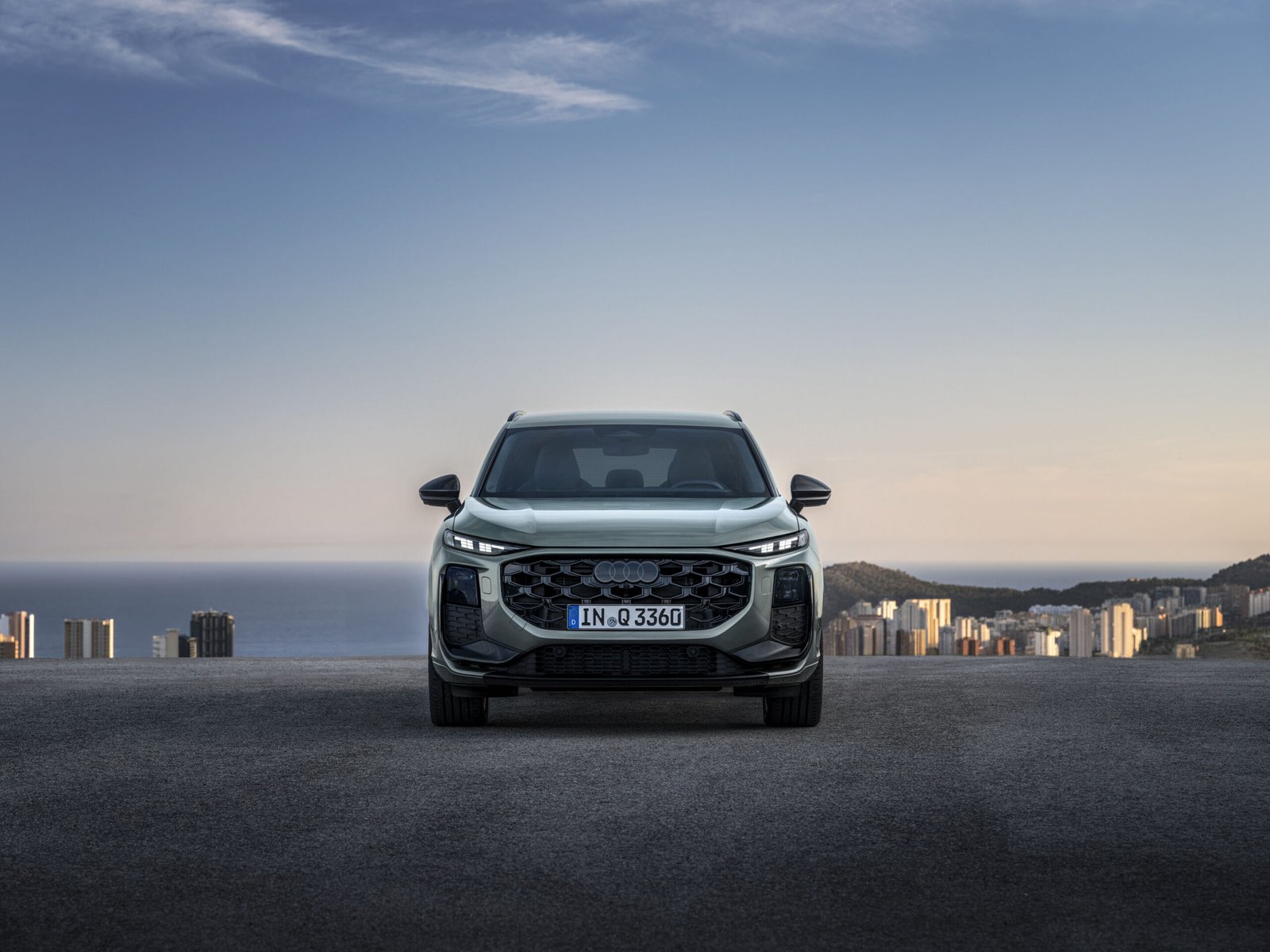 New Audi Q3 front view parked on a hill road overlooking a coastal city