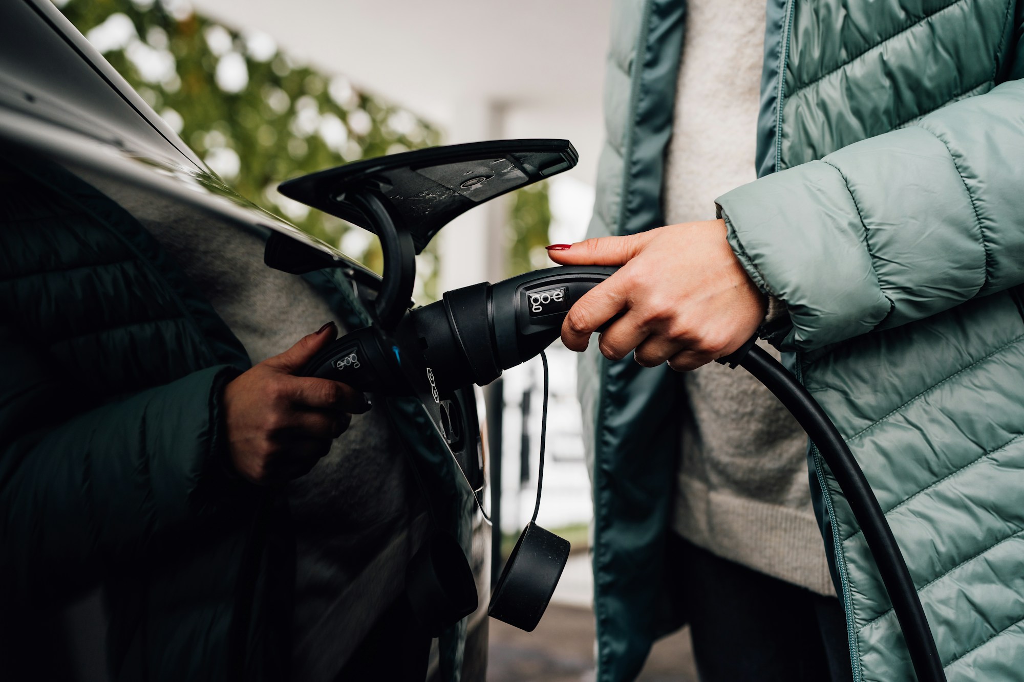 Close-up of a person plugging a charging cable into an electric car