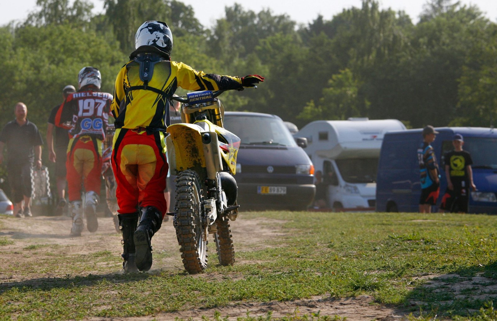 Motocross riders in racing gear walking their dirt bikes off the track