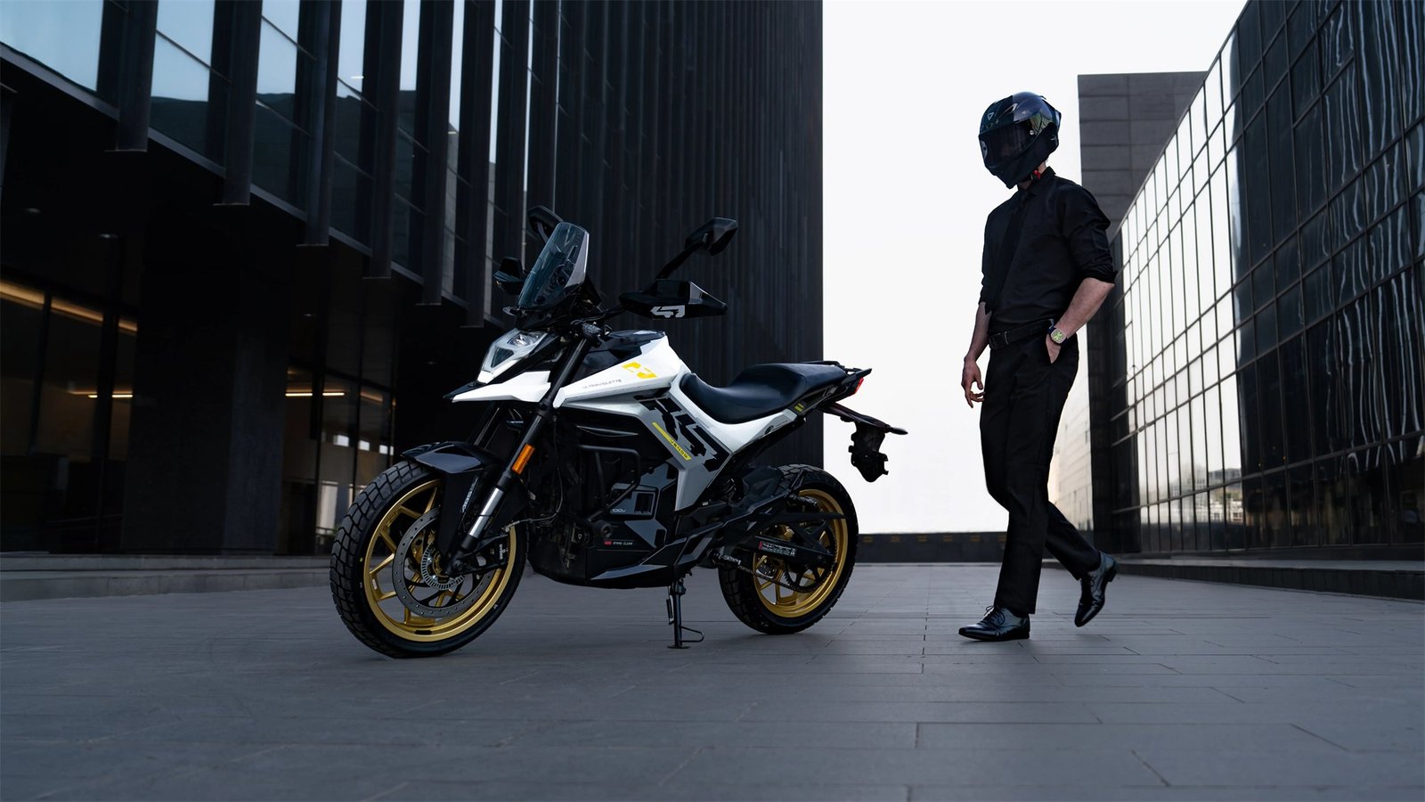 Ultraviolette X-47 Venom parked in an urban plaza at dusk with its rider walking away
