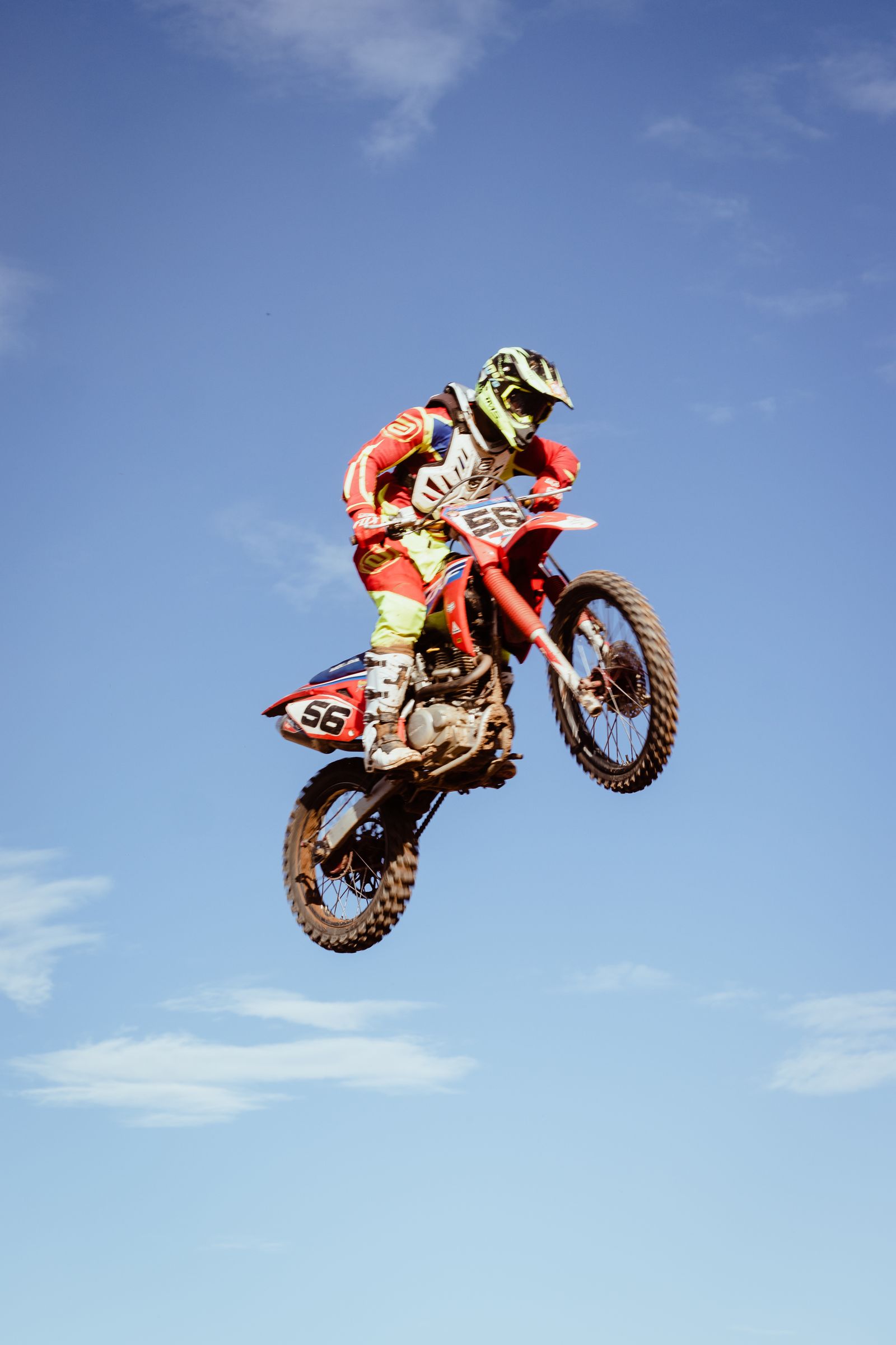 Motocross rider mid-air jump against a blue sky
