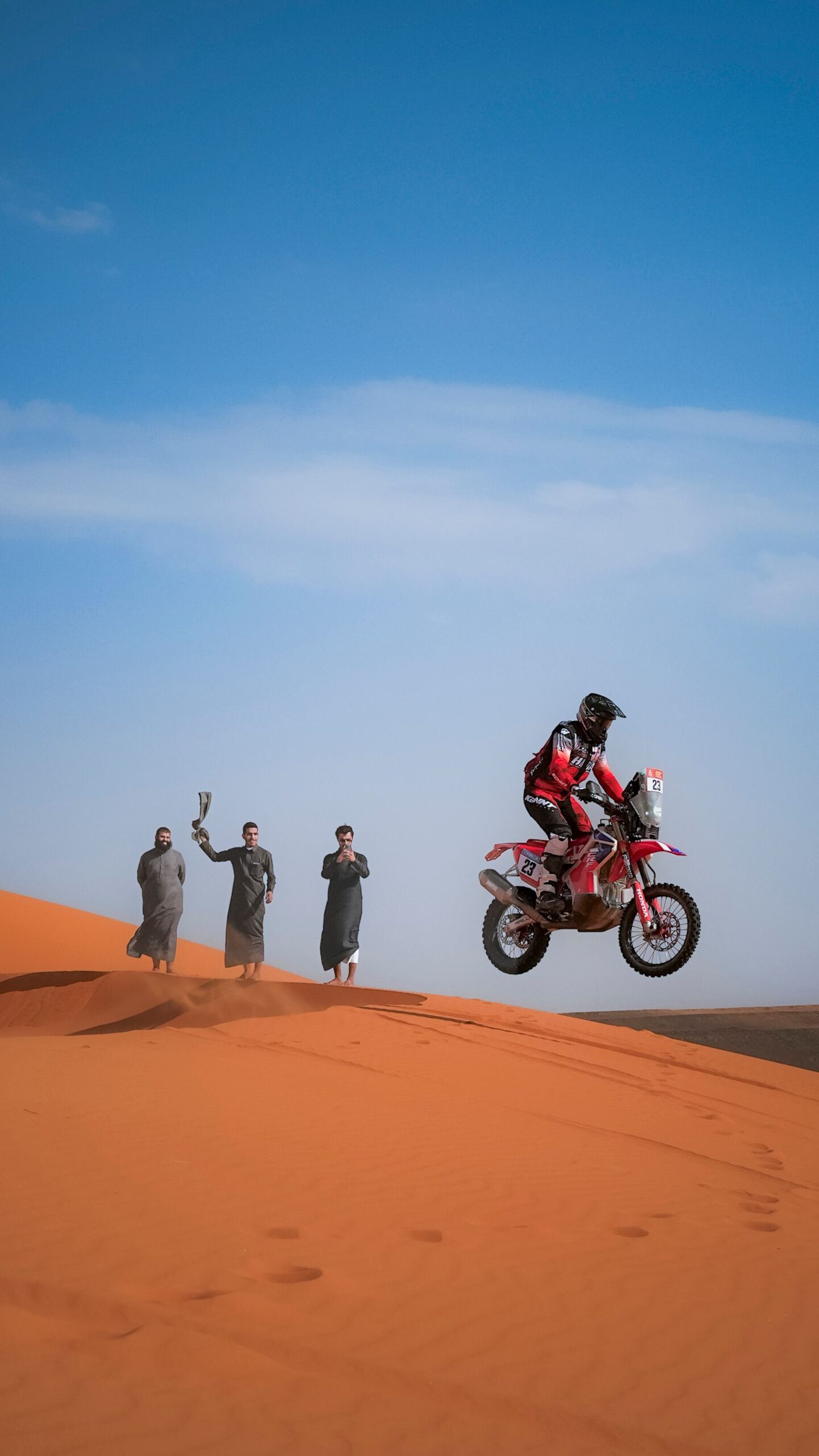 Rally raid motorcycle launching off a sand dune in the desert