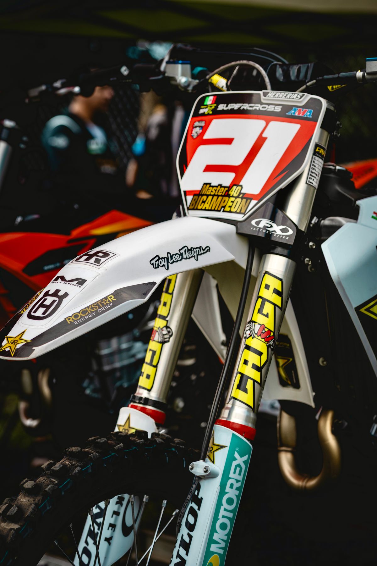 Close-up of a factory motocross bike front fork and number plate with sponsor decals