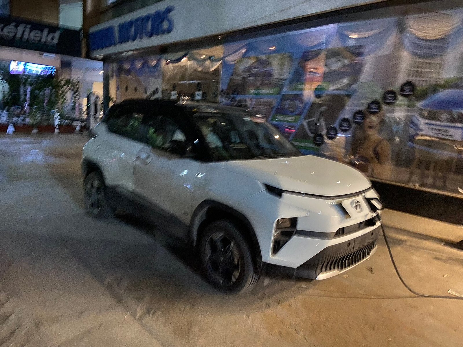 Tata Punch EV plugged into a public charger outside a Tata Motors showroom